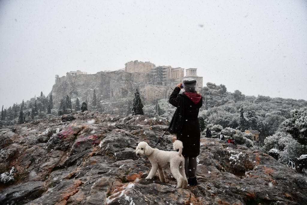 Γυναίκα μαζί με τον σκύλο της φωτογραφίζει την χιονισμένη Ακρόπολη