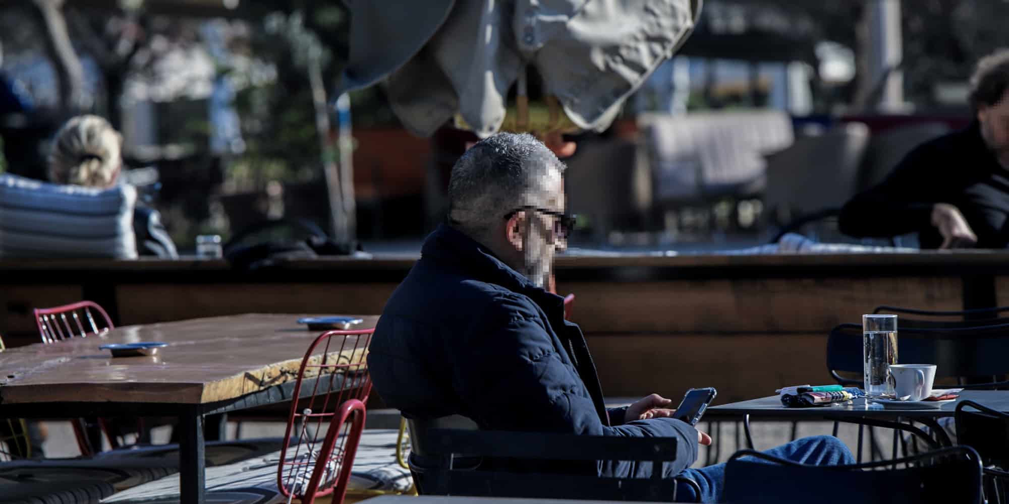Άνδρας ετοιμάζει το πιστοποιητικό εμβολιασμού σε εξωτερικό χώρο καφέ στην Αθήνα