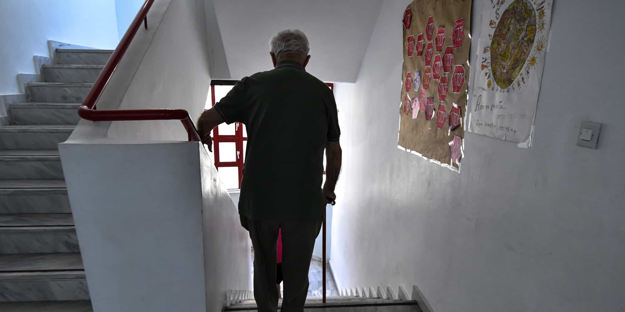 Ηλικιωμένος με μαγκούρα κατεβαίνει σκάλες κτιρίου