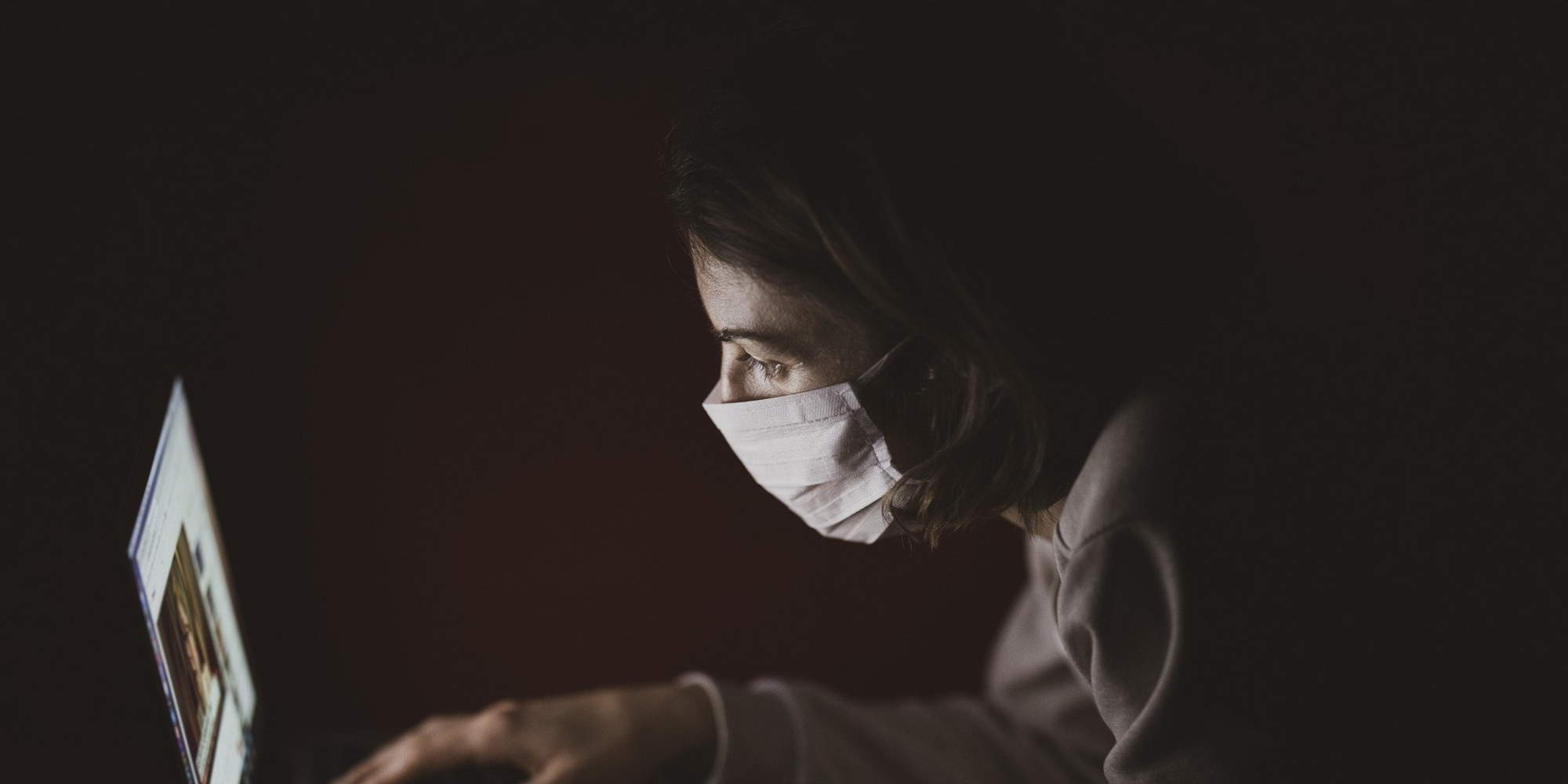 Γυναίκα με μάσκα κατά της Covid μπροστά στον υπολογιστή