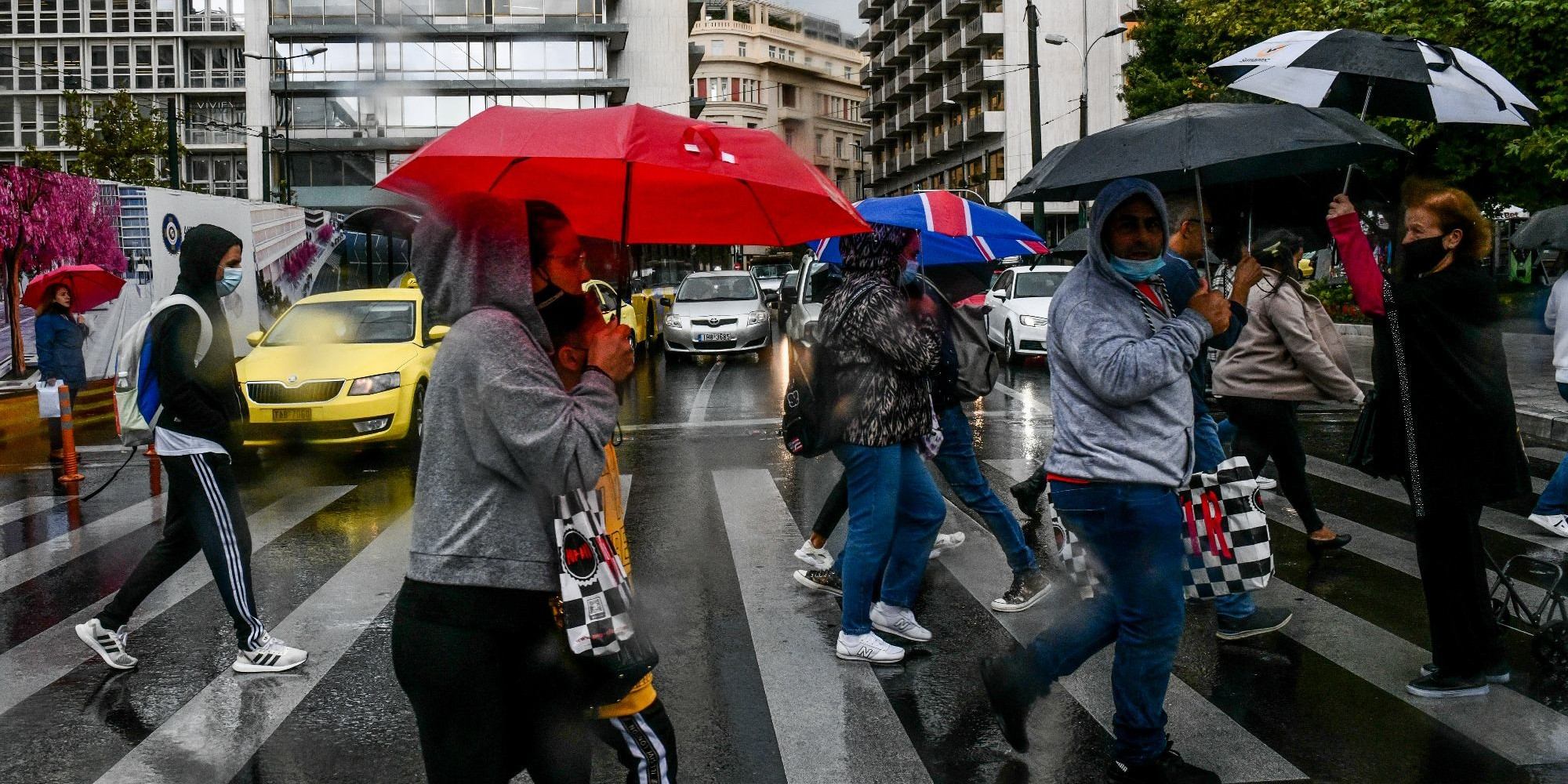 Πολίτες περπατούν με ομπρέλες