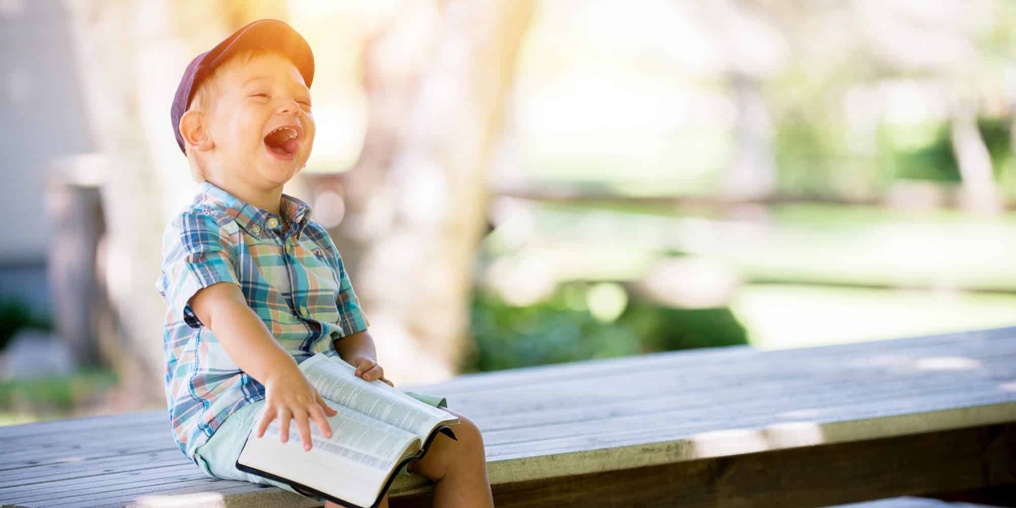 Η ευτυχία ζωγραφισμένη στο γελαστό πρόσωπο ενός παιδιού που κρατά ένα βιβλίο στο παγκάκι
