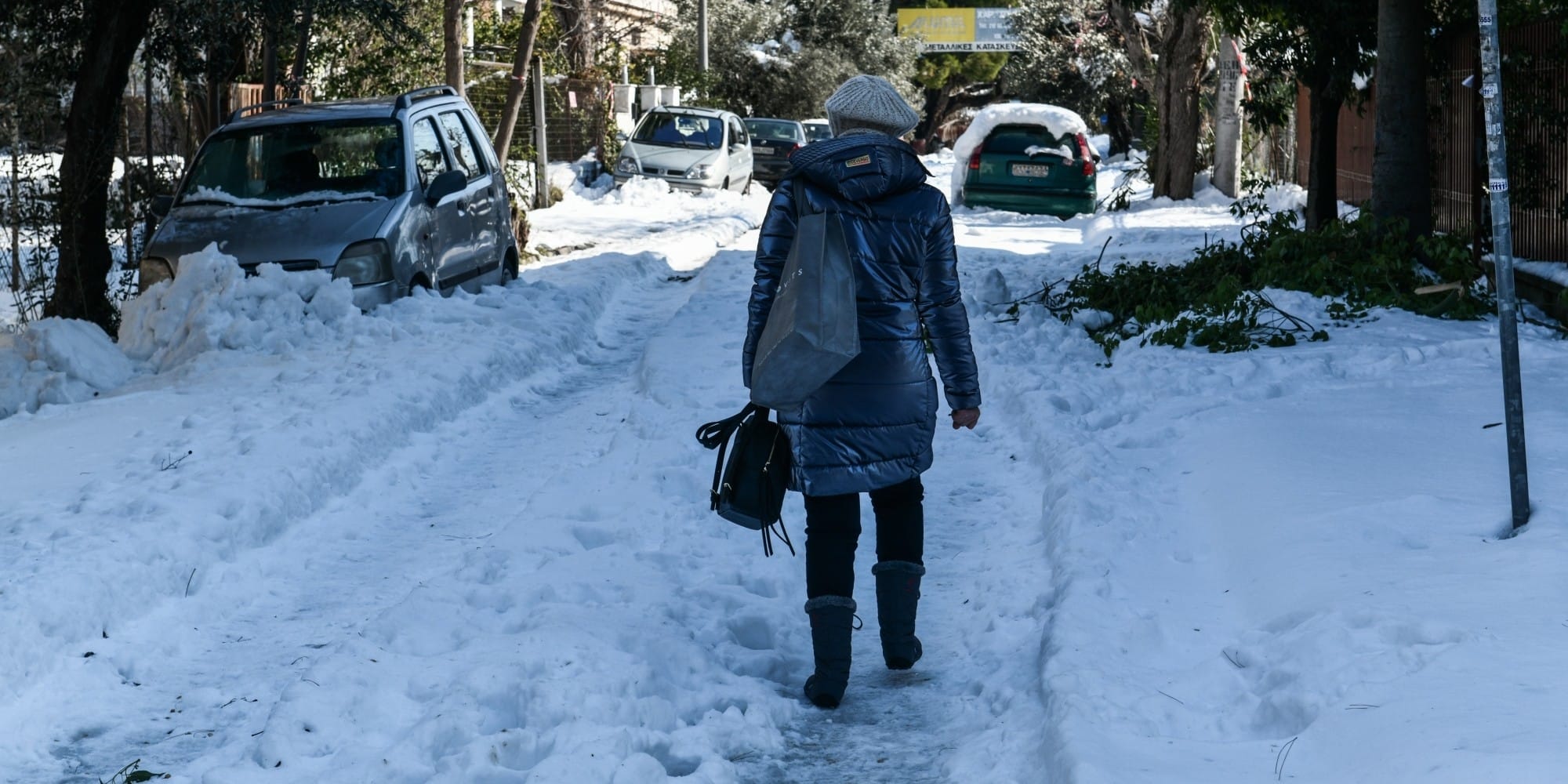 Γυναίκα περπατάει στην χιονισμένη Αττική