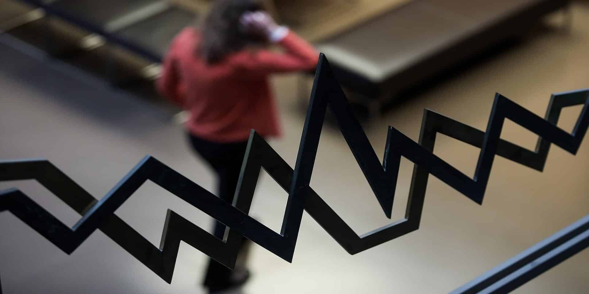 Μια γυναίκα περπατάει μπροστά στον χρηματιστηριακό δείκτη