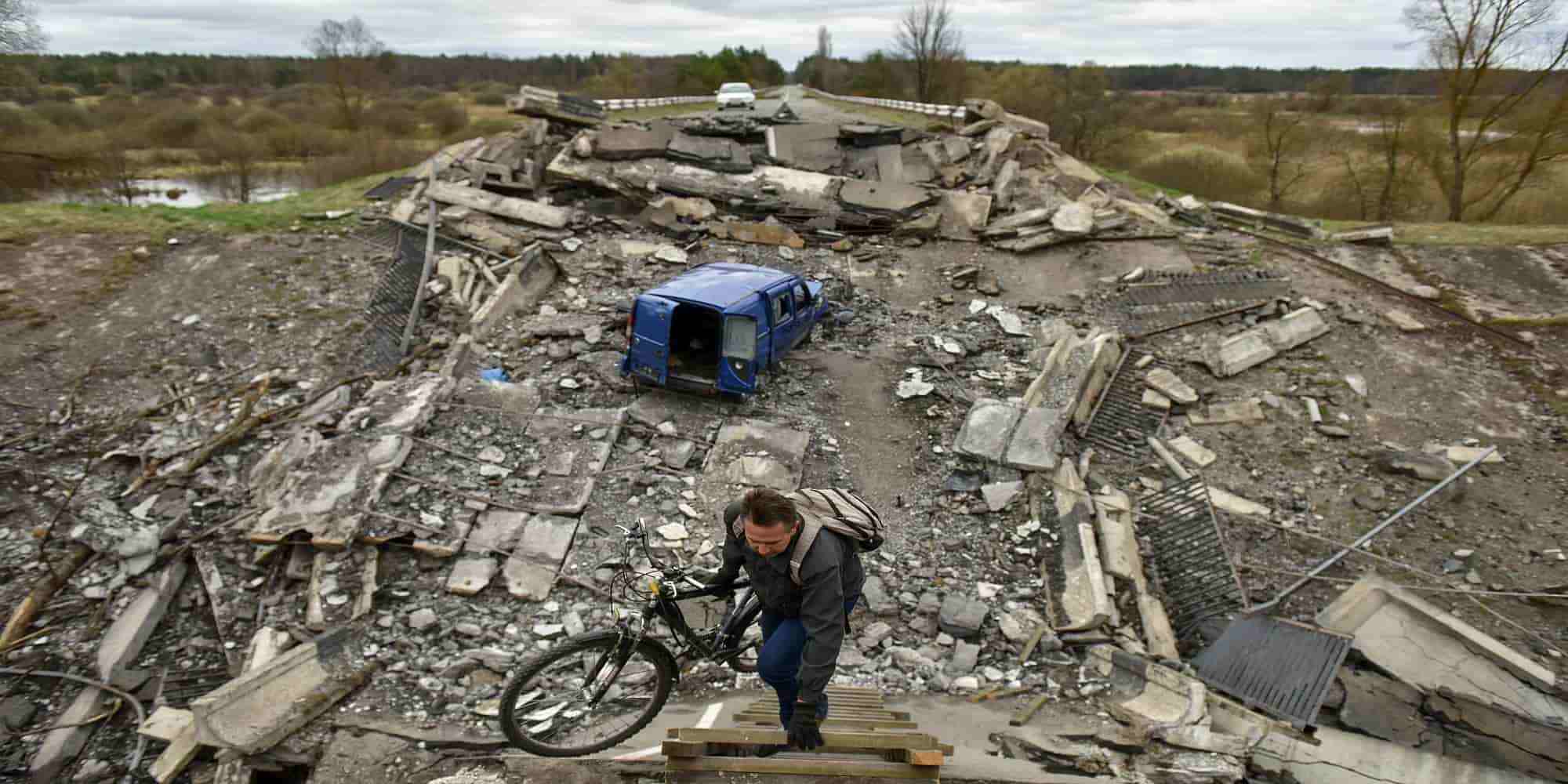 Άνδρας μεταφέρει ένα ποδήλατο πάνω από μια κατεστραμμένη γέφυρα στο Κίεβο