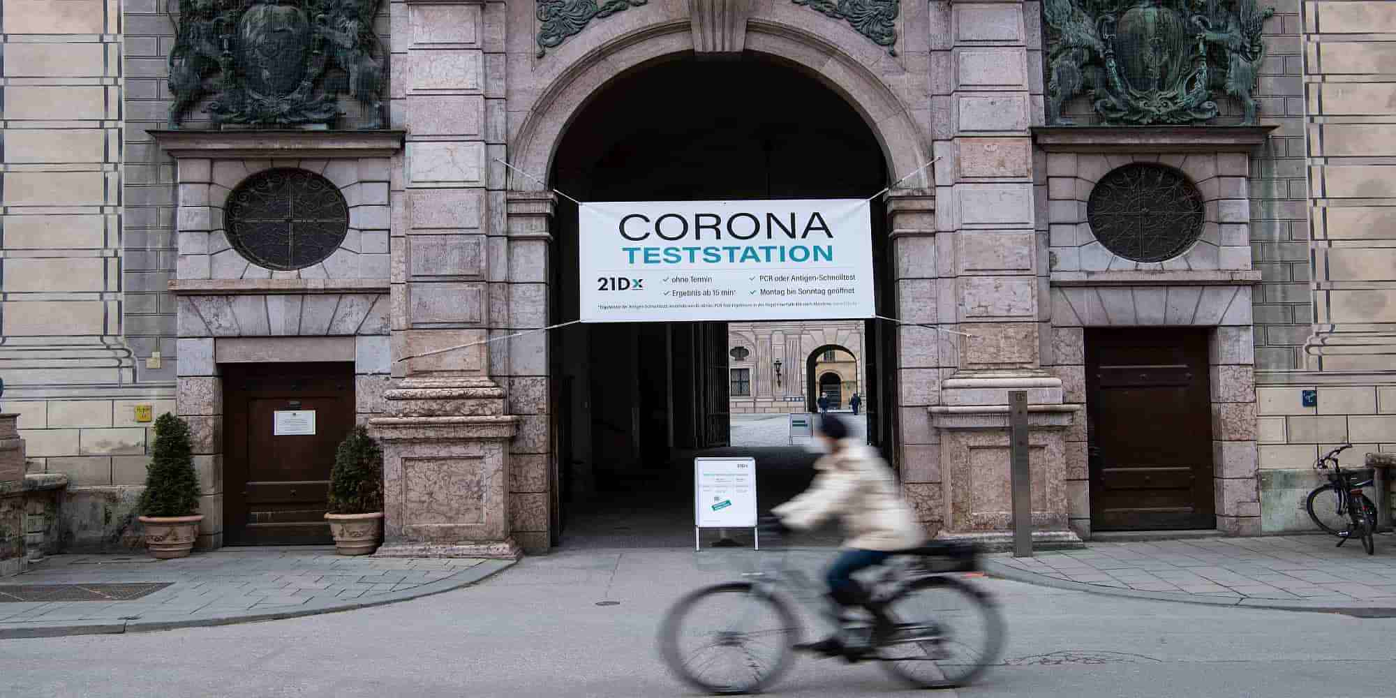 Ποδηλάτης στο Μόναχο, περνά μπροστά από ταμπέλα που γράφει «Corona Teststation»