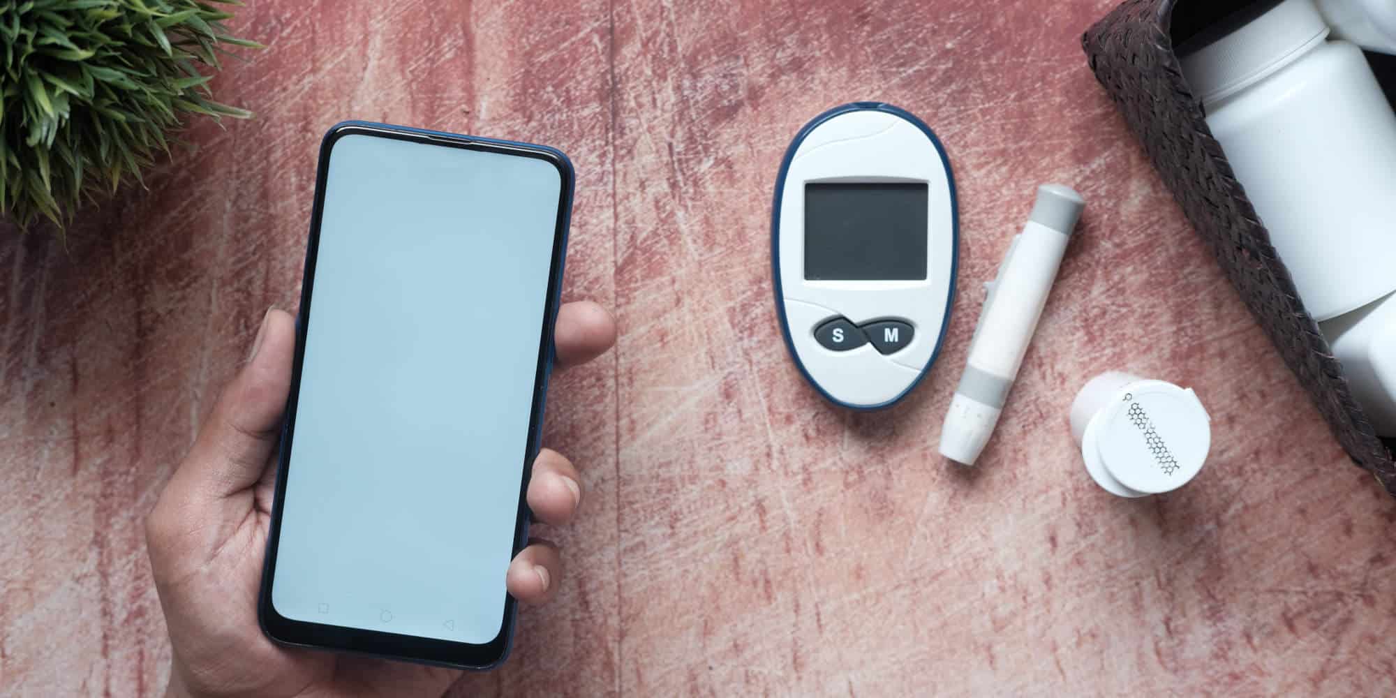 Κινητό τηλέφωνο πλάι σε συσκευή μέτρησης ζαχάρου για τον διαβήτη