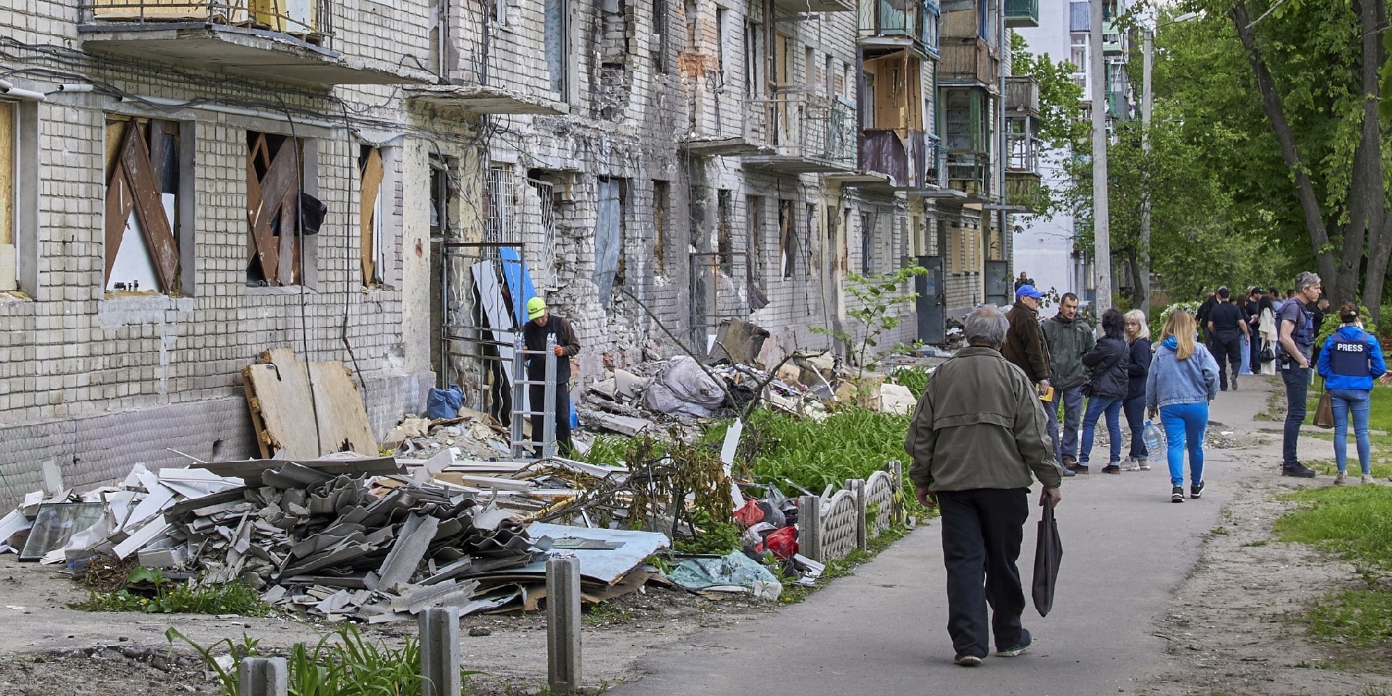 Ουκρανοί περπατούν μπροστά από κατεστραμμένο κτίριο στο Χάρκοβο, στην Ουκρανία