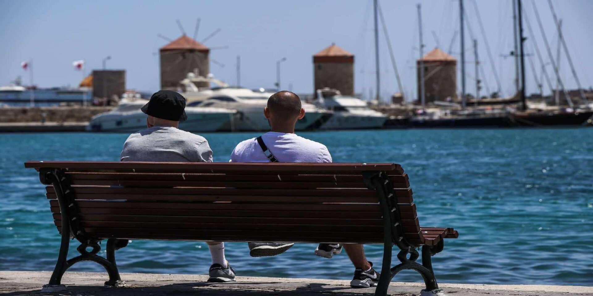 Ανθρωποι κάθονται στο παγκάκι στο λιμάνι της Ρόδου