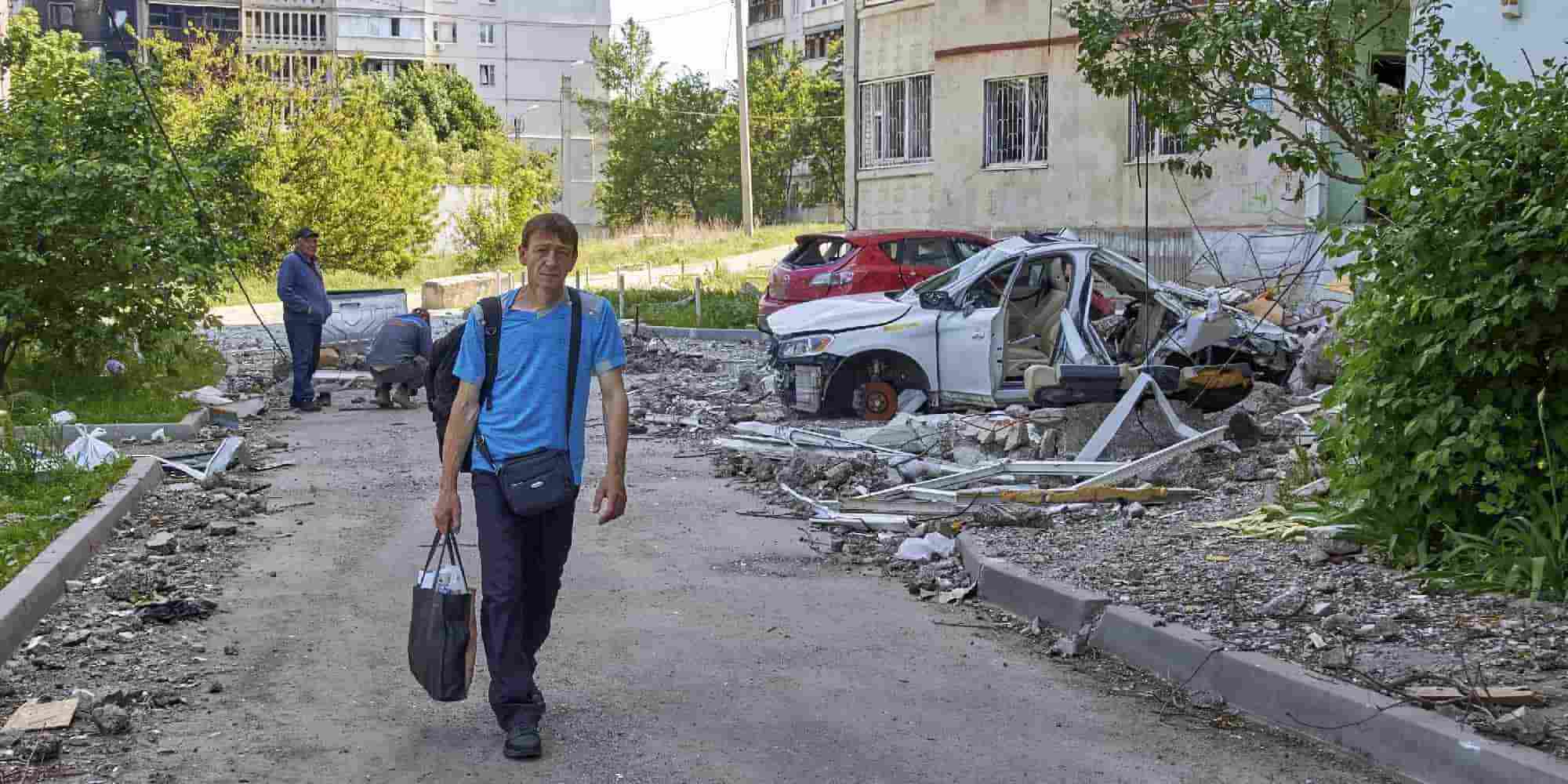 Ουκρανός περπατάει μπροστά από κατεστραμμένα σπίτια και αυτοκίνητα στο Χάρκοβο της Ουκρανίας