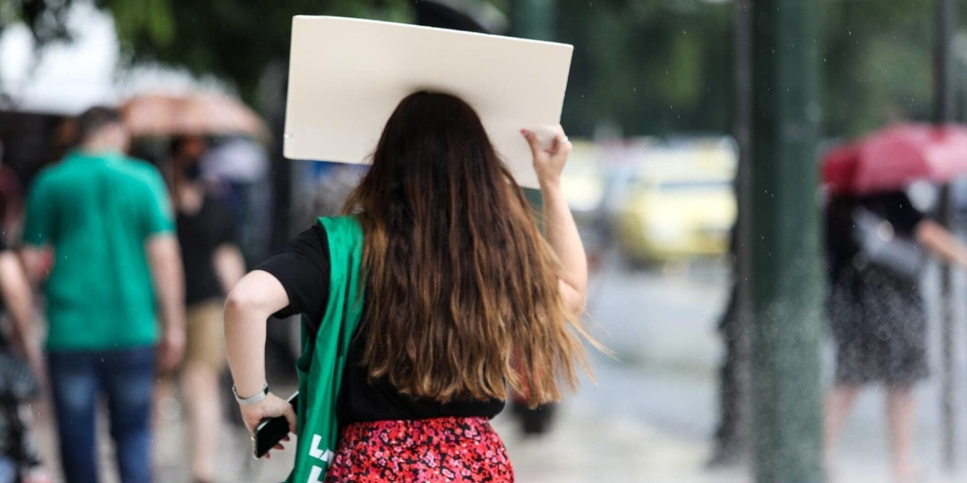 Πολίτες περπατούν στο κέντρο της Αθήνας, την ώρα που έπιασε μπόρα