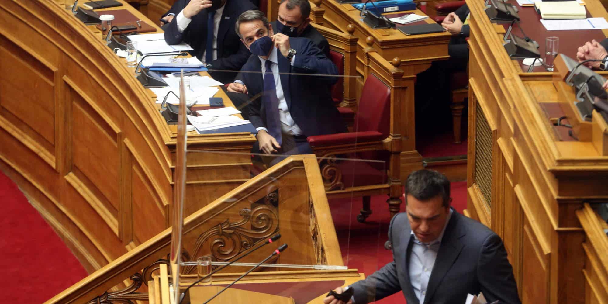 Ο Κυριάκος Μητσοτάκης παρακολουθεί τον Αλέξη Τσίπρα να αποχωρεί από το βήμα της Βουλής