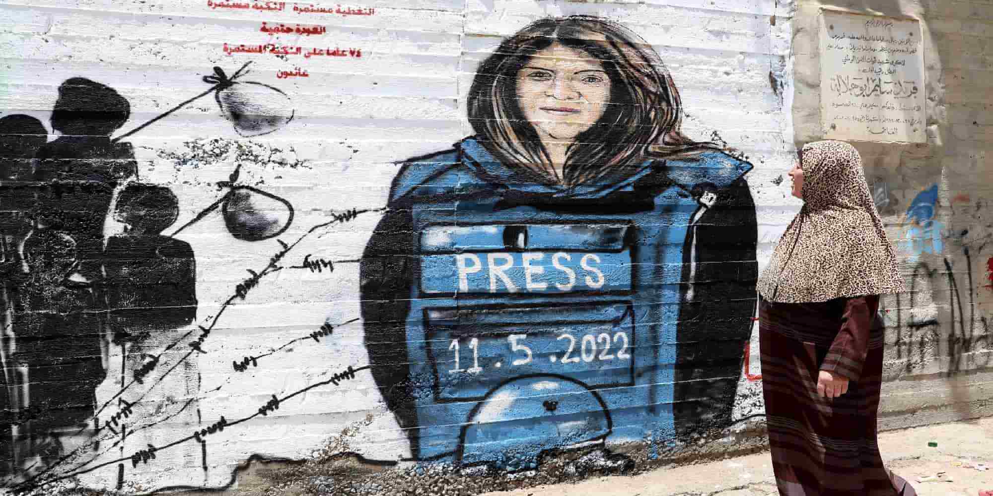 Παλαιστίνιοι περπατούν μπροστά από ένα γκράφιτι με τη δολοφονημένη δημοσιογράφο Σιρίν Αμπού Άκλεχ