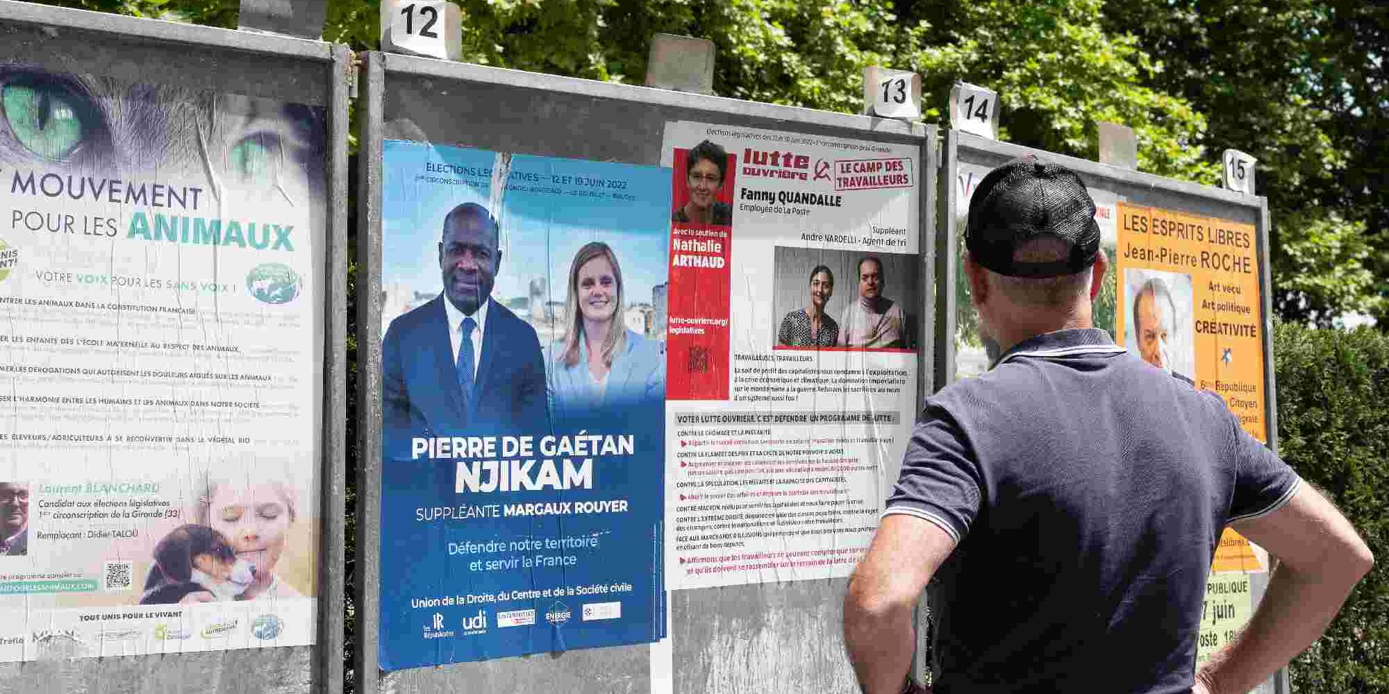 Aνδρας στέκεται μπροστά από αφίσες για τον δεύτερο γύρο των βουλευτικών εκλογών στη Γαλλία