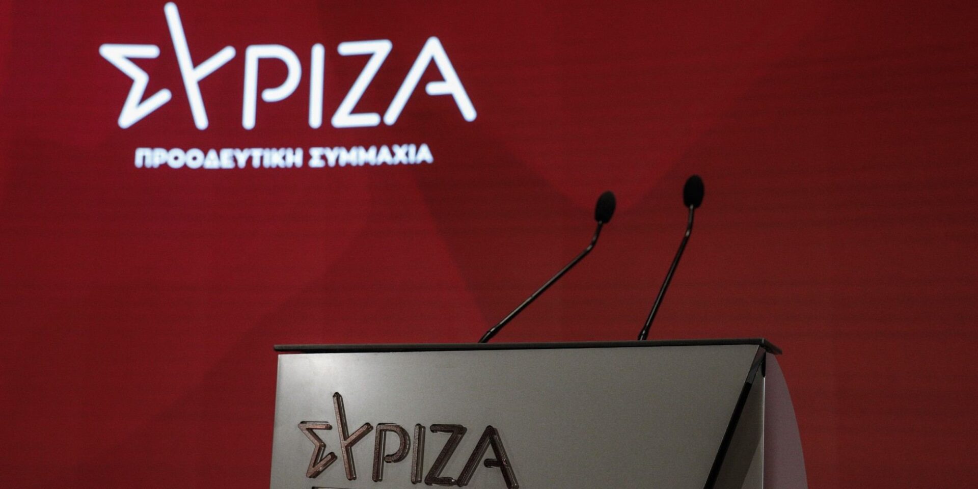 Λογότυπο του ΣΥΡΙΖΑ και μικρόφωνα στη συνεδρίαση της Κεντρικής Επιτροπής