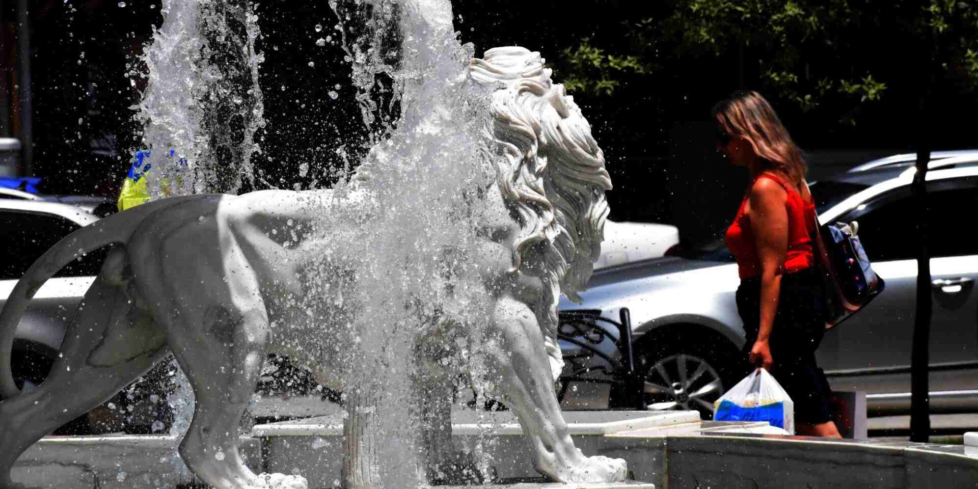 Κυρία περνάει μπροστά από ένα συντριβάνι