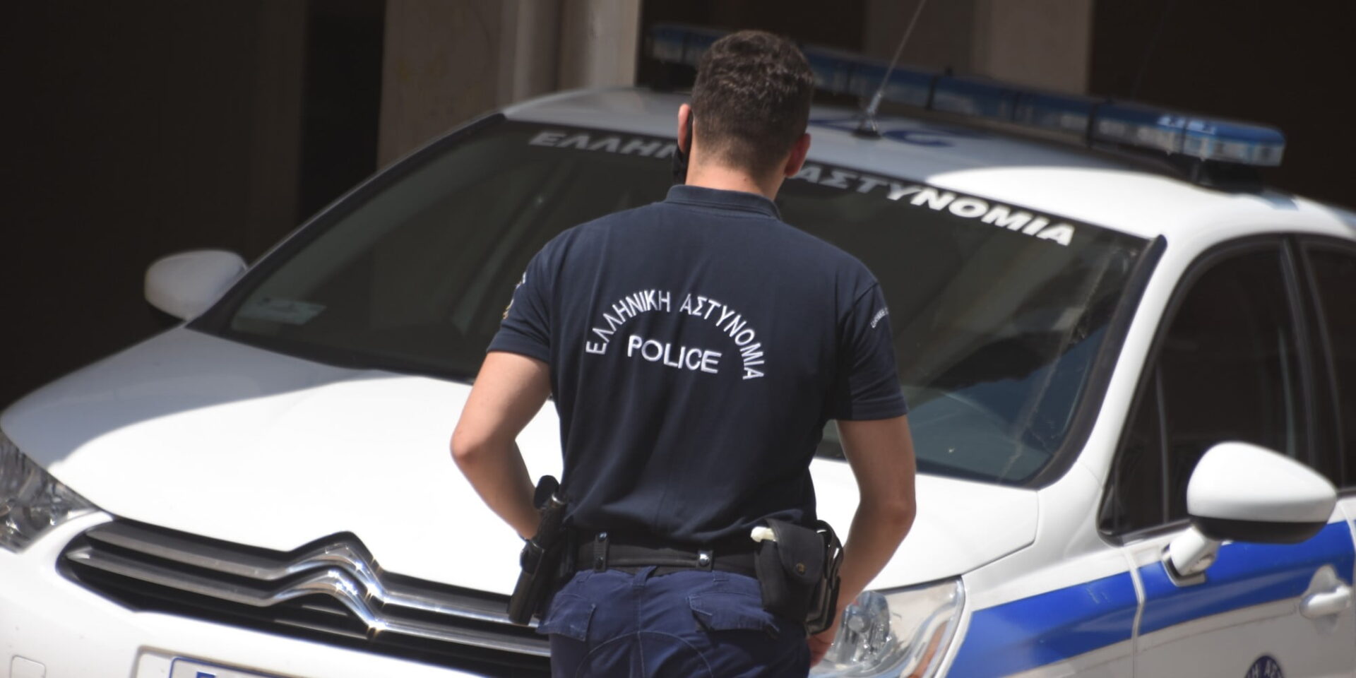 Αστυνομικός μπροστά από περιπολικό