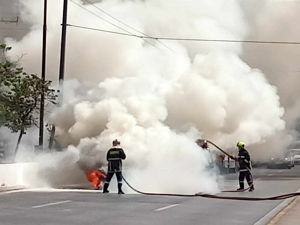 Πυροσβέστες σβήνουν το αυτοκίνητο που τυλίχθηκε στις φλόγες στην Συγγρού