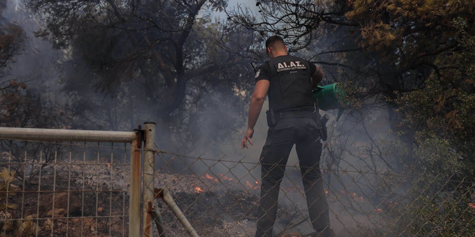 Αστυνομικός με κουβά ρίχνει νερό στη φωτιά