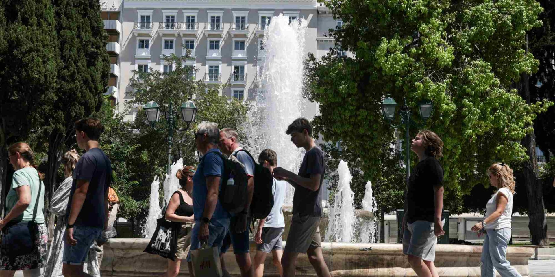 Κόσμος περνά μπροστά στο σιντριβάνι στο κέντρο της Αθήνας
