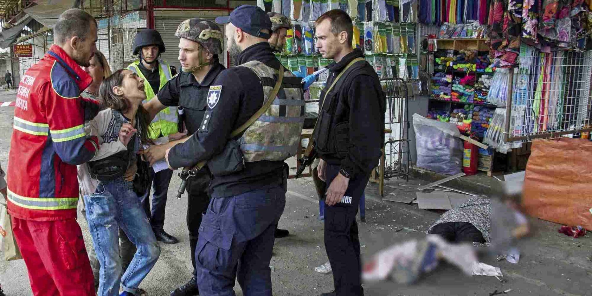 Νοσηλευτές και αστυνομικοί ηρεμούν μια γυναίκα που ο άντρας της πέθανε μετά από ρωσική πυραυλική επίθεση σε στάση λεωφορείου στο Χάρκοβο
