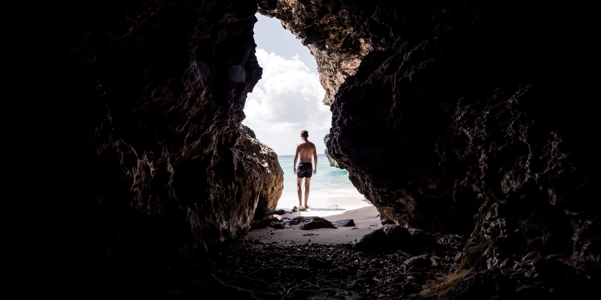 Άνδρας περνά μέσα από μια σπηλιά και βγαίνει σε ειδυλλιακή παραλία