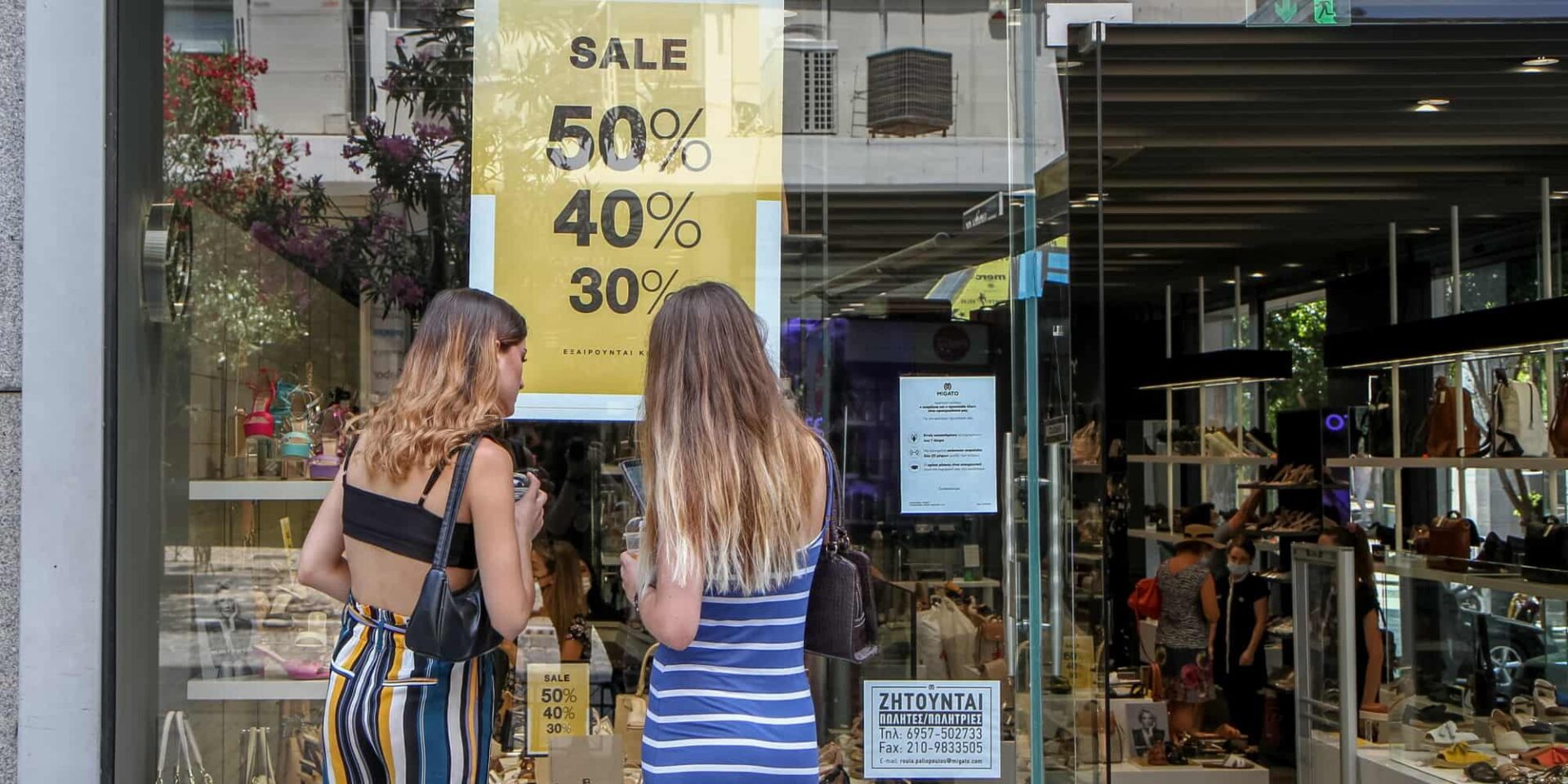 Κοπέλες κοιτούν κατάστημα στις θερινές εκπτώσεις