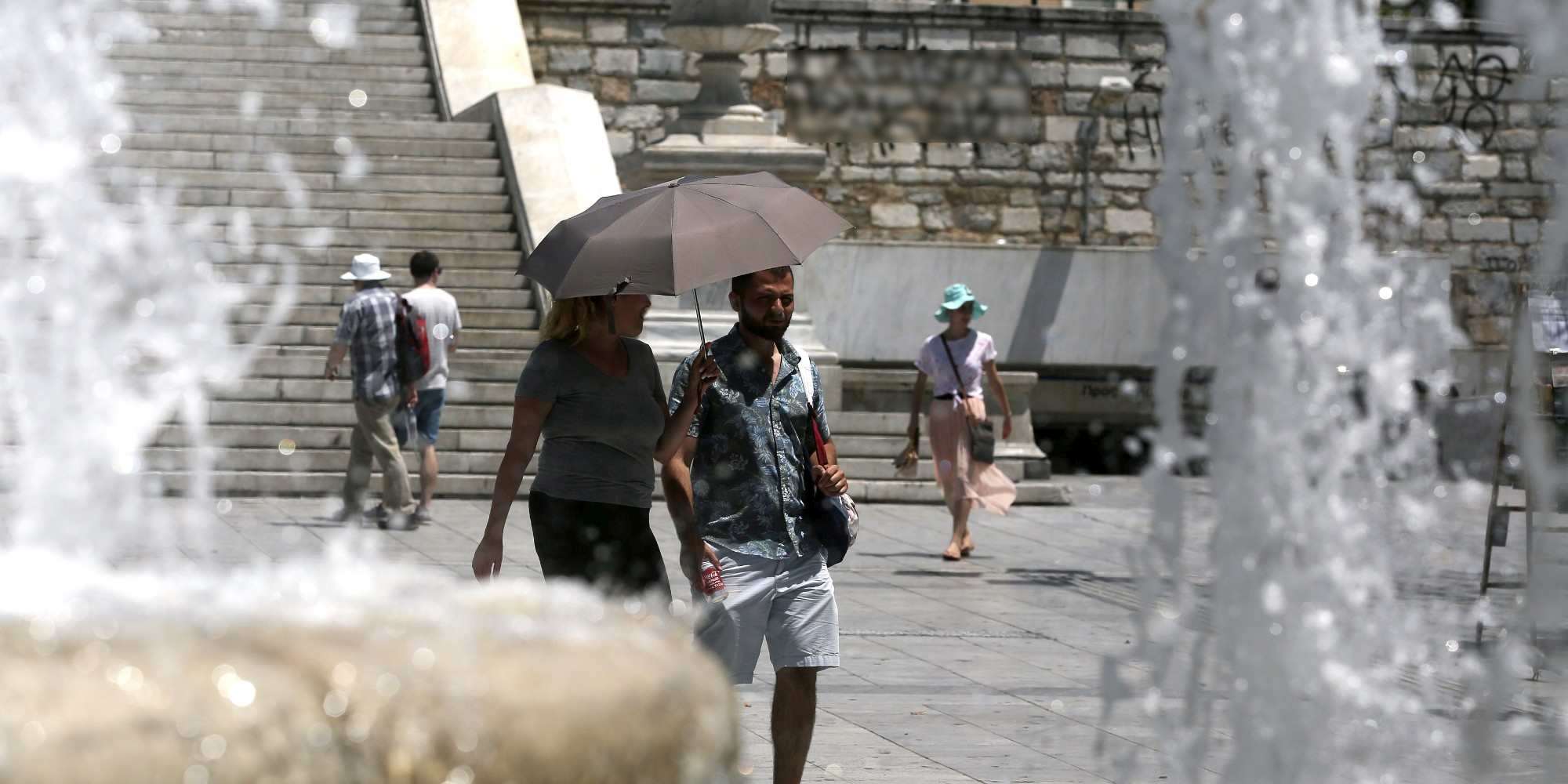 Πολίτες με καπέλα και ομπρέλες στο κέντρο της Αθήνας