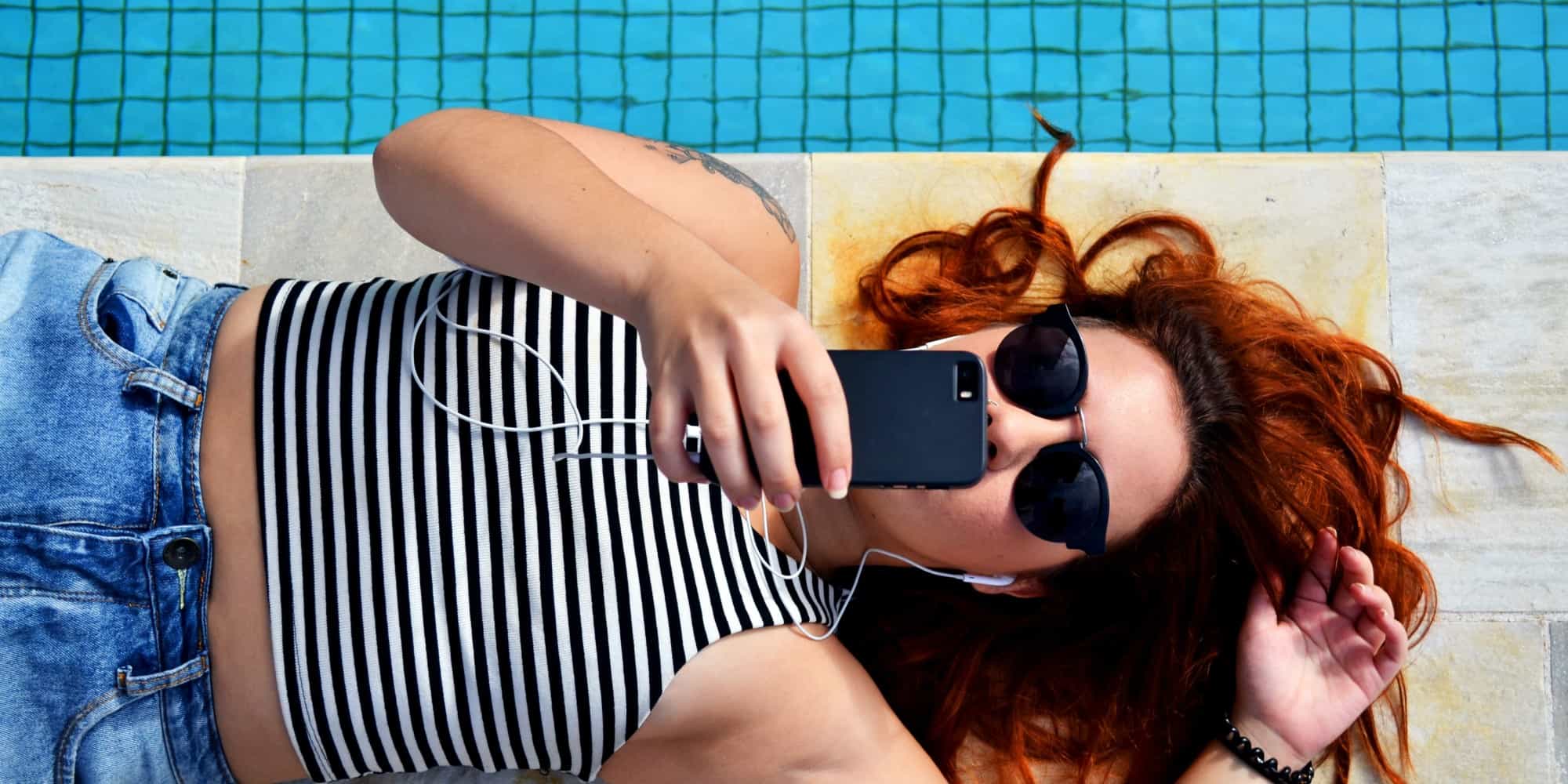 Κοπέλα με το κινητό της δίπλα σε πισίνα