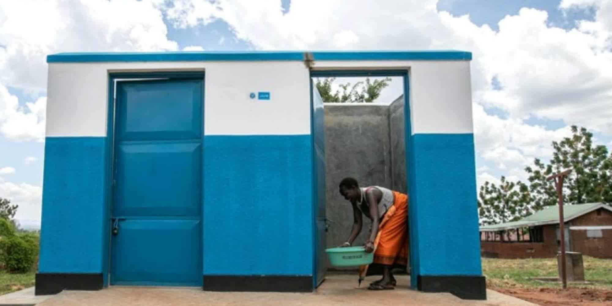 Υγειονομική εγκατάσταση στην Αφρική, όπου γυναίκα μεταφέρει νερό με λεκάνη