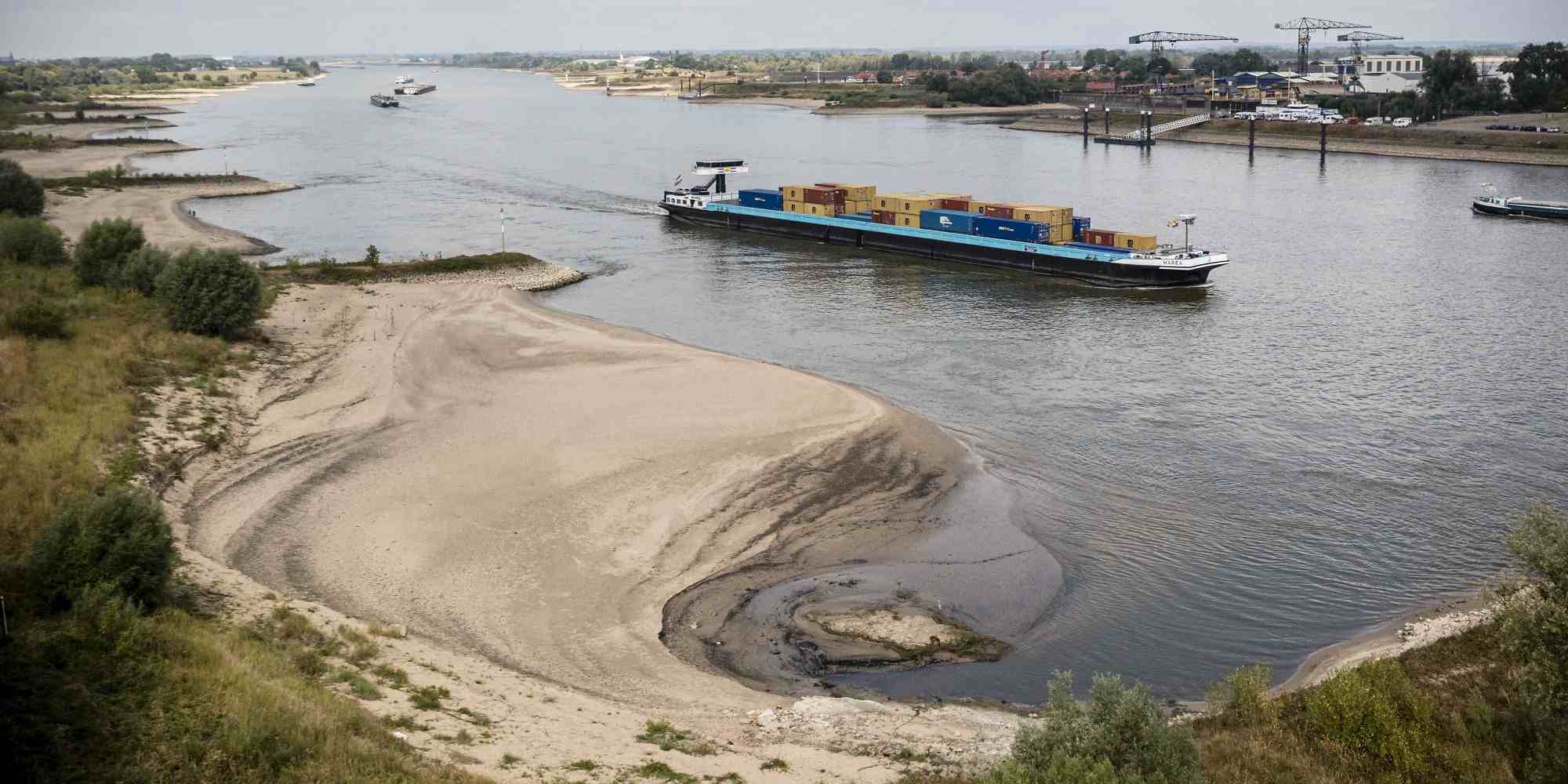 Φορτηγό πλοίο πλέει κατά μήκος μιας αμμώδους όχθης στις όχθες του ποταμού Ρήνου στην Ολλανδία, που έχει υποχωρήσει η στάθμη του