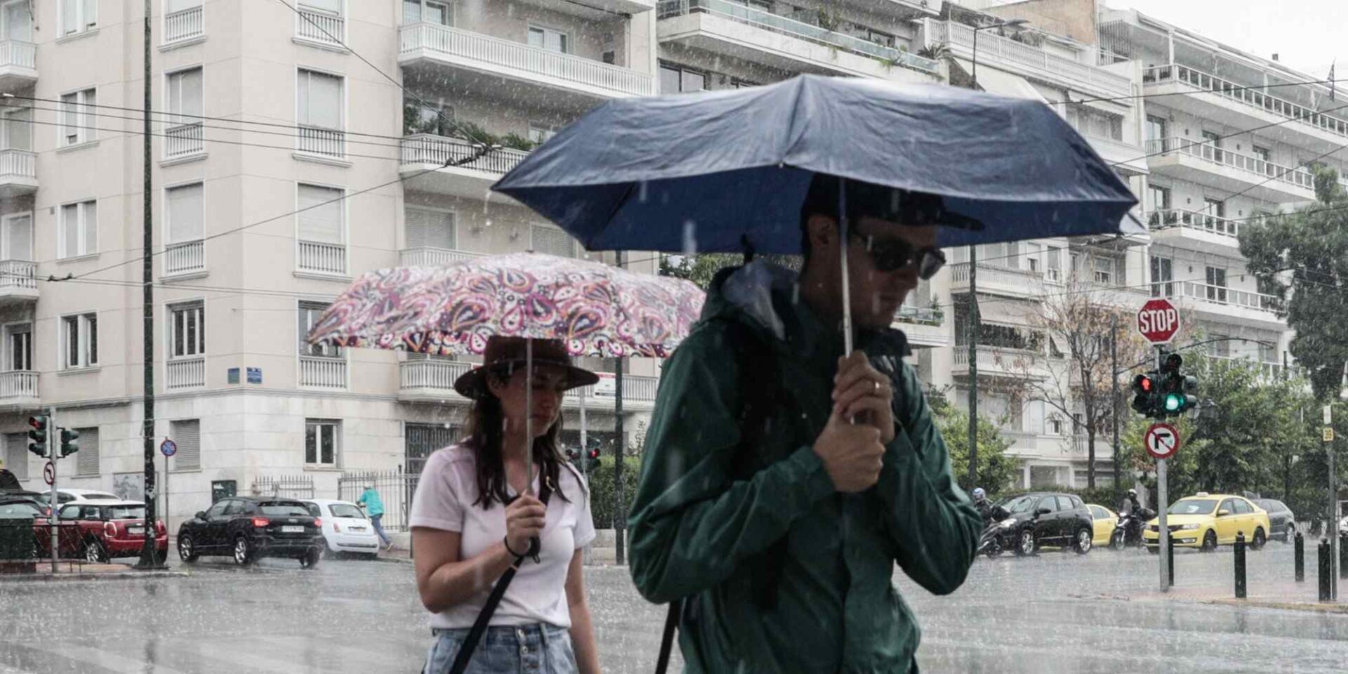 Πολίτες περπατούν στην βροχερή Αθήνα με ομπρέλες