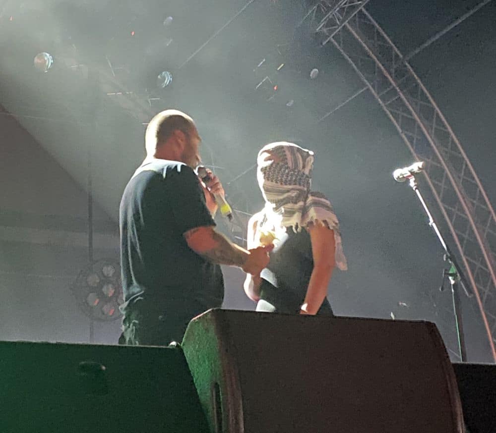 Ο Βέβηλος δίνει λευκό τριαντάφυλλο σε γυναίκα με μαντίλα στο Off The Hook Festival 