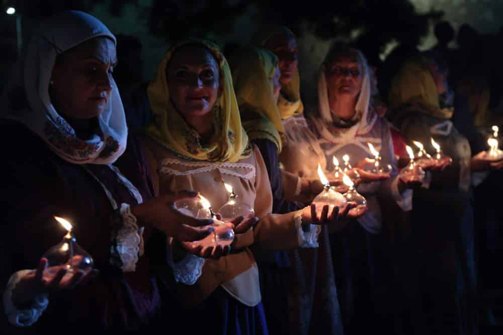 Γυναίκες με παραδοσιακές φορεσιές κρατούν αναμμένα κεριά