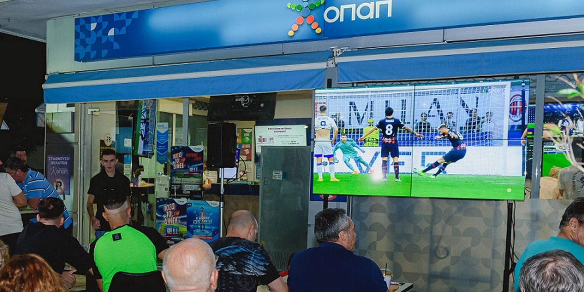 Κόσμος βλέπει ποδόσφαιρο σε ΟΠΑΠ