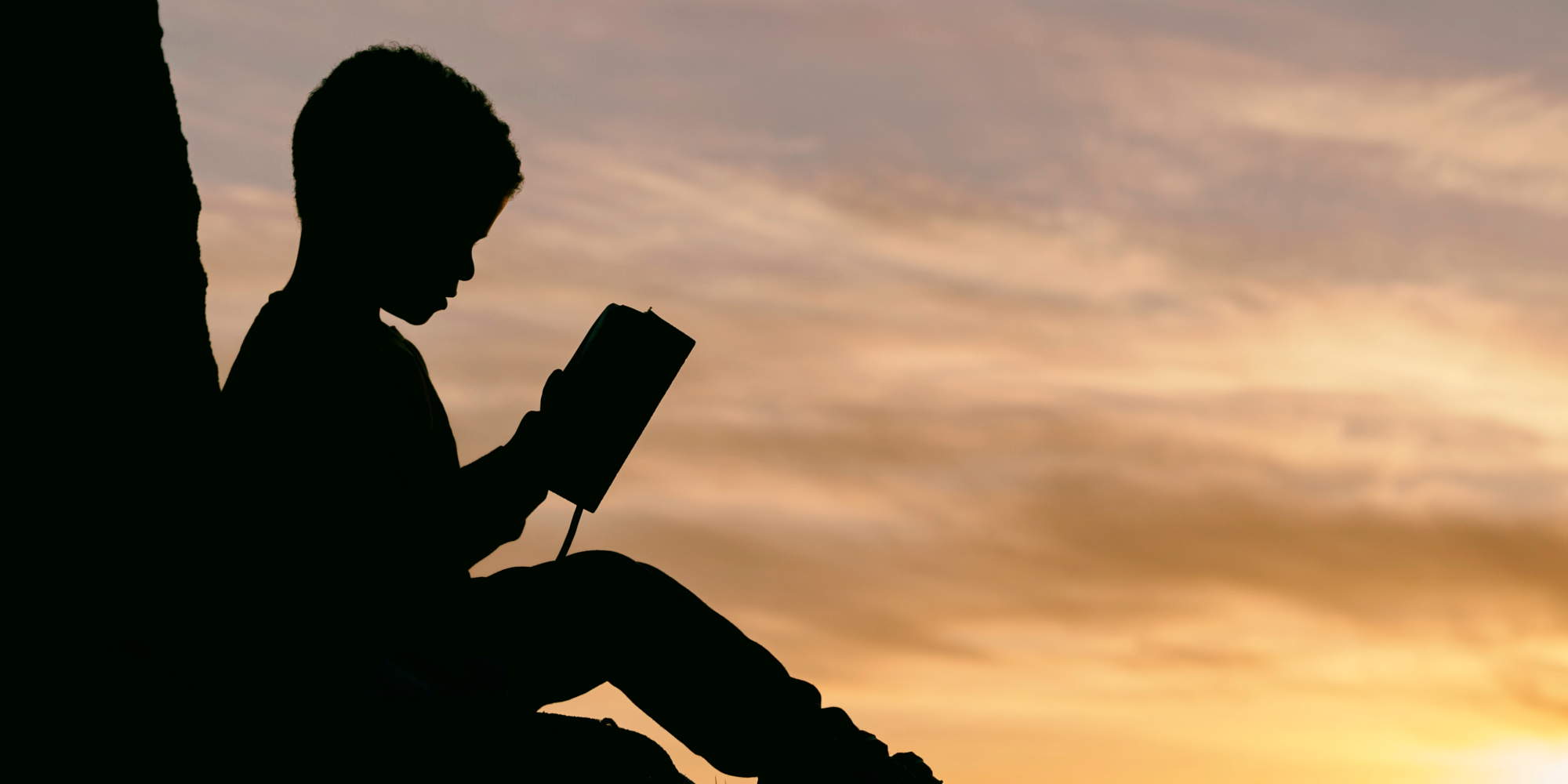 Παιδάκι διαβάζει βιβλίο στο ηλιοβασίλεμα
