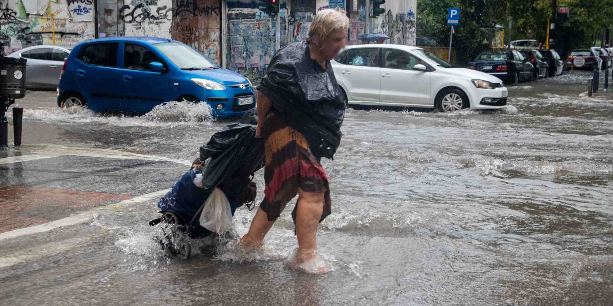 Γυναίκα προσπαθεί να διασχίσει πλημμυρισμένο δρόμο στην Θεσσαλονίκη