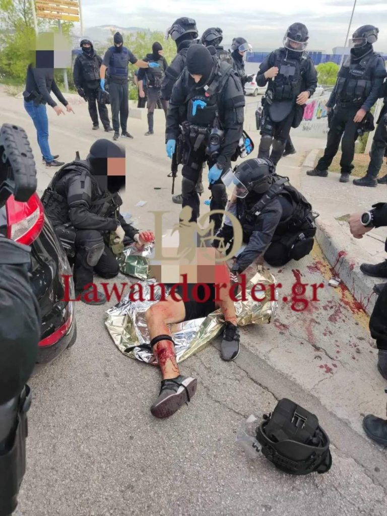 Ο Αλβανός κακοποιός κείτεται στο έδαφος με αίματα και δέχεται τις πρώτες βοήθειες από τους άνδρες της ΕΛΑΣ