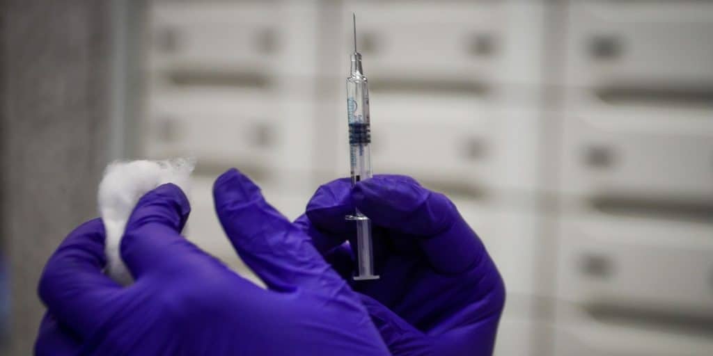 Νοσοκόμα με μπλε γάντια κρατά εμβόλιο για την γρίπη