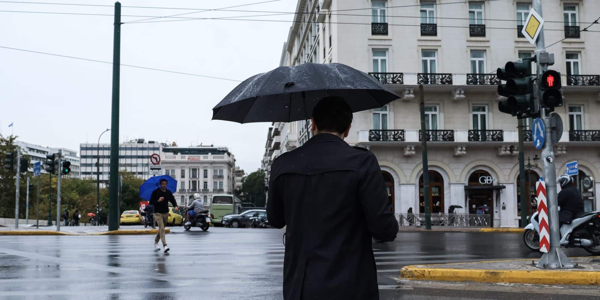 Άνδρας με ομπρέλα στο κέντρο της Αθήνας, σε βροχερό καιρό