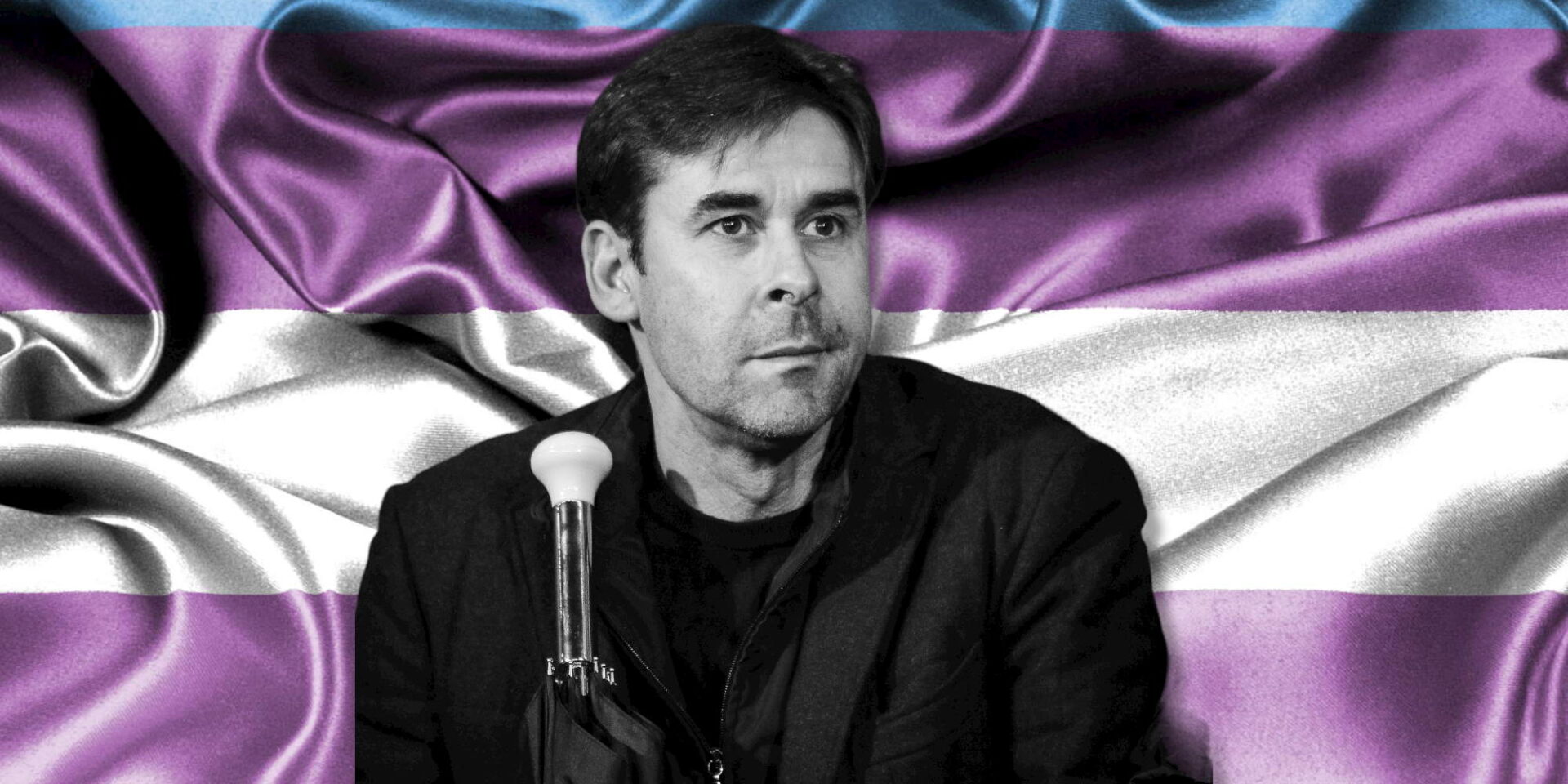 Ο Βασίλης Τσιάρτας με φόντο τη σημαία των διεμφυλικών