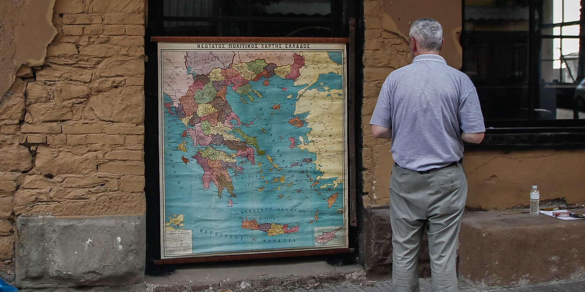 Ηλικιωμένος άνδρας μπροστά σε χάρτη της Ελλάδας