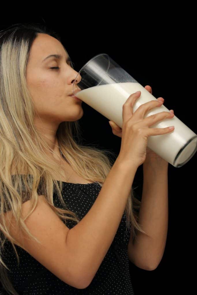 Γυναίκα πίνει από ένα πελώριο ποτήρι γάλα