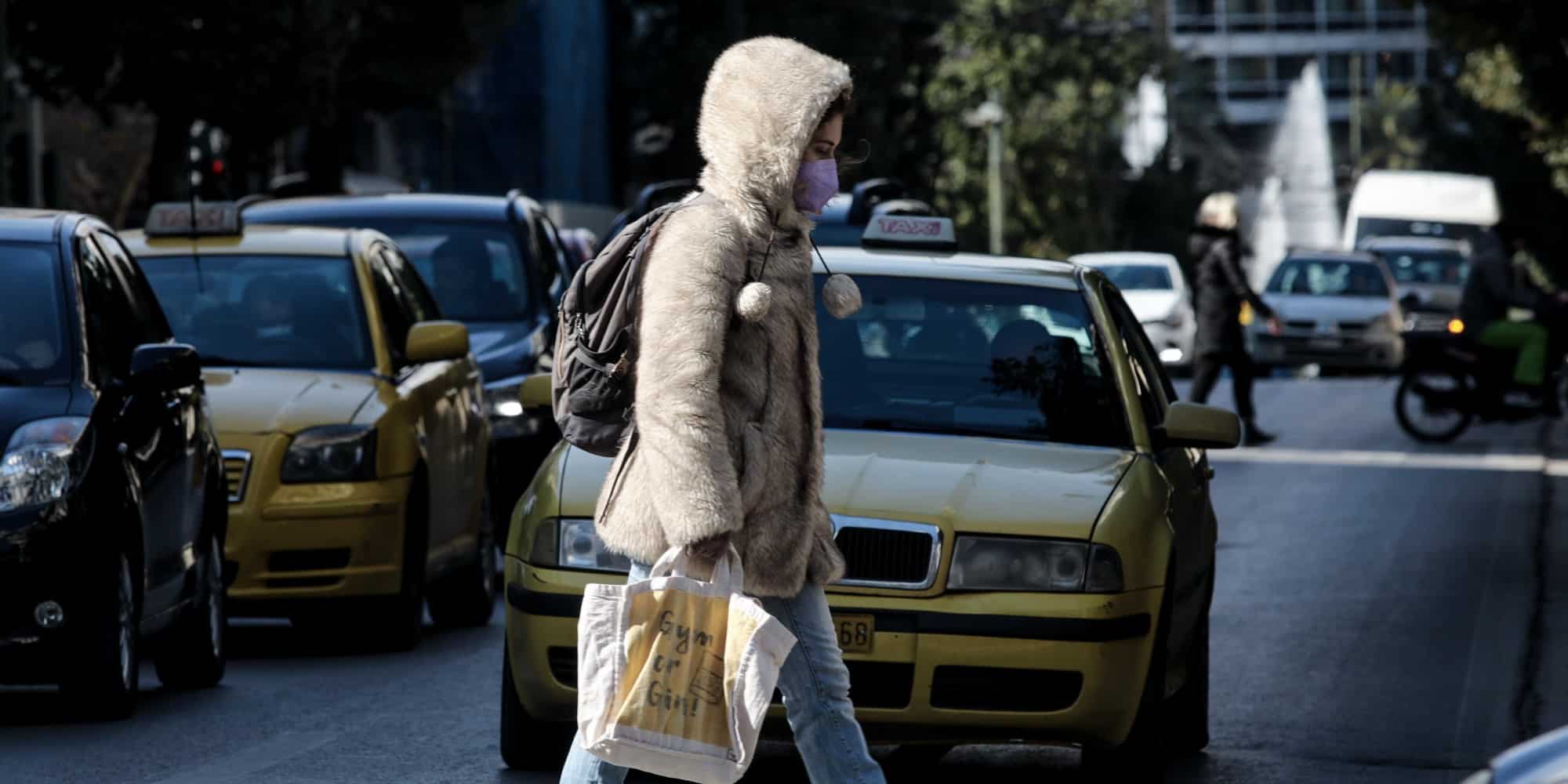 Γυναίκα μέσα στο κρύο περπατά στην Αθήνα