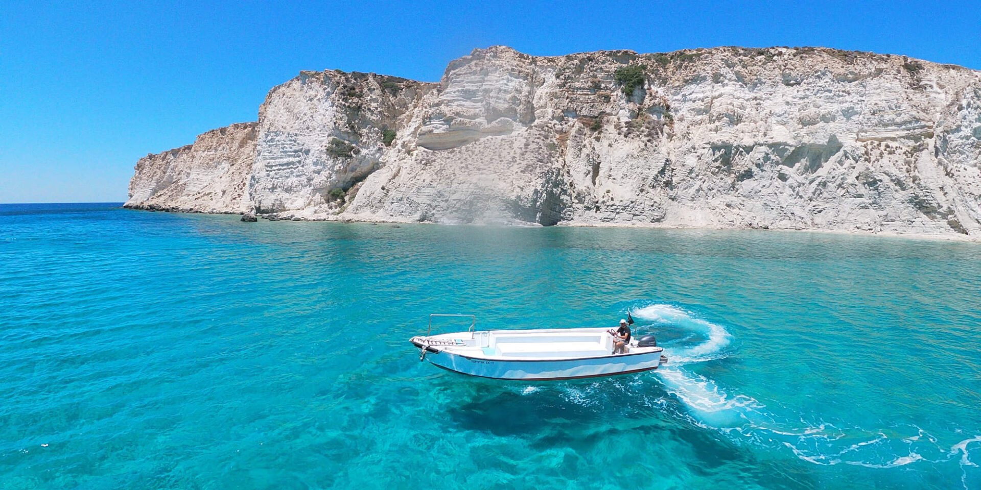 Μία βάρκα μέσα στη θάλασσα με φόντο ένα βουνό