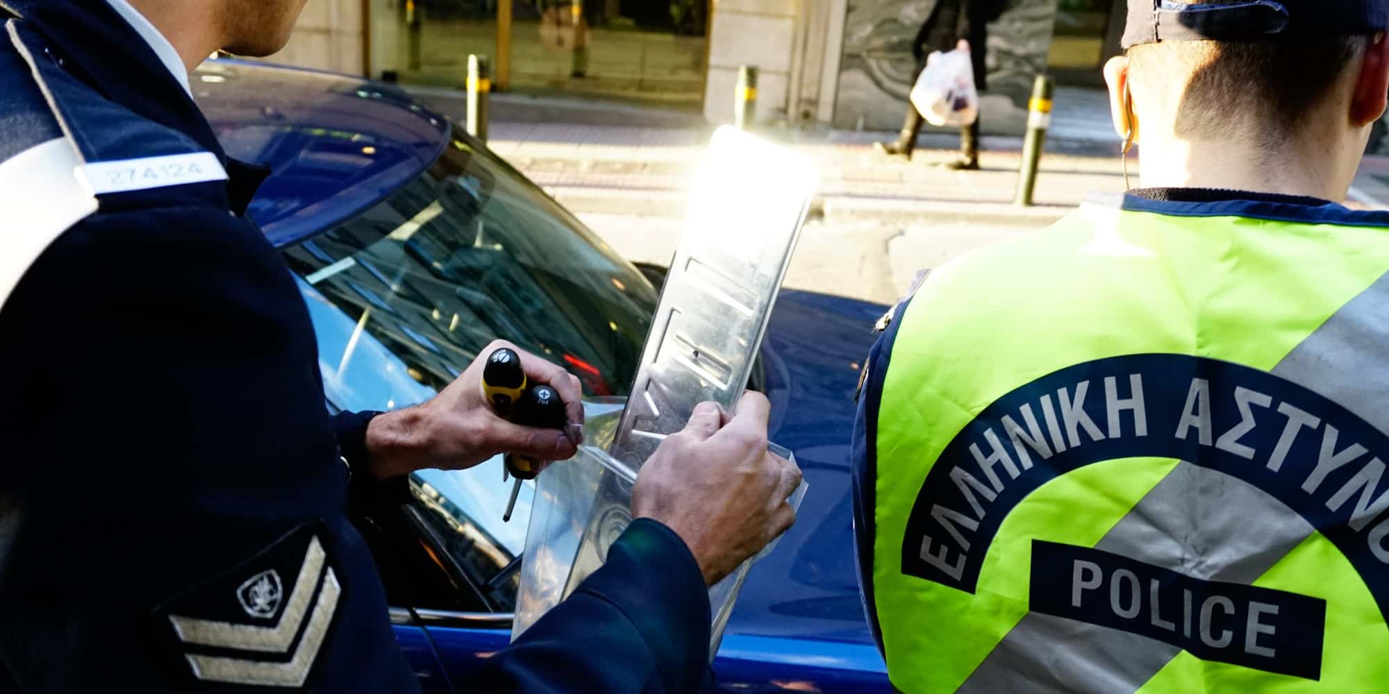 Αστυνομικός αφαιρεί πινακίδες από αυτοκίνητο παράνομα παρκαρισμένο