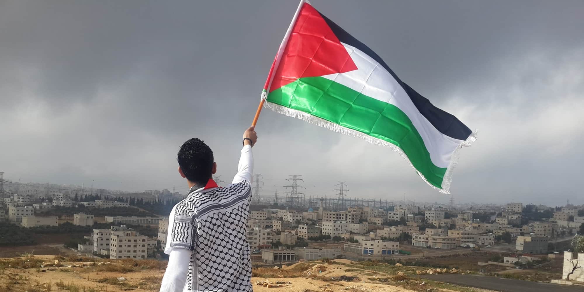 Άνδρας με τη σημαία της Παλαιστίνης με φόντο το Ισραήλ